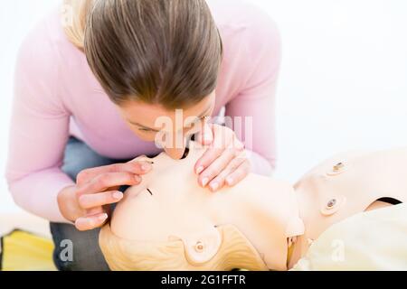 La femme s'entraîne dans le don de souffle bouche-à-bouche sur mannequin Banque D'Images