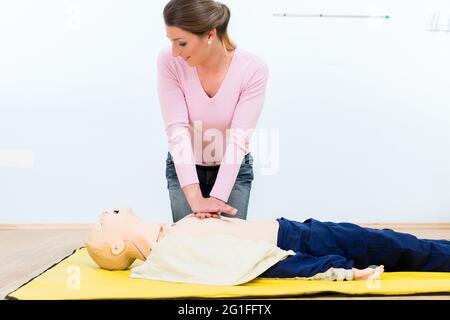 Femme en cours de premiers soins pratiquant un massage cardiaque sur mannequin Banque D'Images