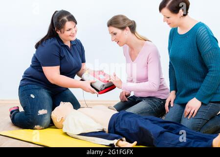 Les stagiaires en premiers soins apprennent à utiliser le défibrillateur pour la réanimation dans le cours de premiers soins Banque D'Images