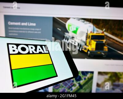 Téléphone portable avec logo de la société australienne de matériaux Boral Limited à l'écran en face de la page Web d'affaires. Effectuez la mise au point au centre-droit de l'écran du téléphone. Banque D'Images