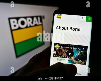 Personne tenant un téléphone portable avec le site Web de la société australienne de matériaux Boral Ltd à l'écran devant le logo. Concentrez-vous sur le centre de l'écran du téléphone. Banque D'Images