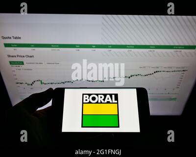 Personne tenant un smartphone avec le logo de la société australienne de matériaux Boral Limited à l'écran devant le site Web. Mise au point sur l'affichage du téléphone. Banque D'Images