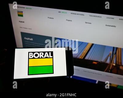 Personne tenant un téléphone portable avec le logo de la société australienne de matériaux Boral Ltd à l'écran en face de la page Web d'affaires. Mise au point sur l'affichage du téléphone. Banque D'Images