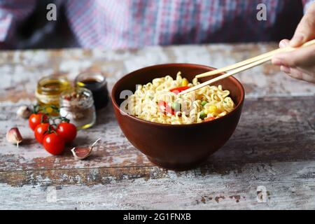 Les mains masculines mangent des nouilles chinoises avec des baguettes. Nouilles épicées de style chinois. Soupe de nouilles. Banque D'Images