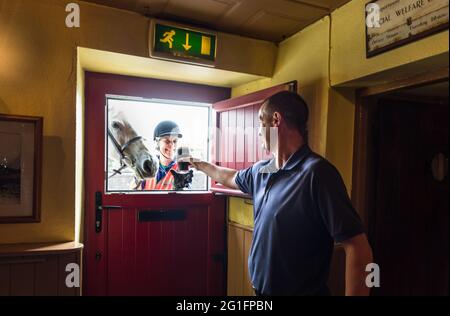 Roberts Cove, Cork, Irlande. 07e juin 2021. Avec l'entrée en vigueur de l'assouplissement des restrictions Covid-19, le public Frank Walsh sert une pinte de crème suinte à travers la demi-porte à son premier client en six mois Imogen Bertin et son cheval Hatbox quand ils ont appelé au bar de la baie de Roberts Cove, Co. Cork, Irlande. - crédit; David Creedon / Alamy Live News Banque D'Images