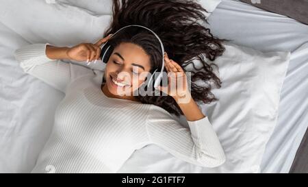 Jeune femme afro-américaine satisfaite à l'écoute de musique Banque D'Images