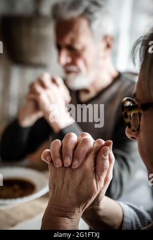 Couple senior chrétien priant à la table adorant le Seigneur Banque D'Images