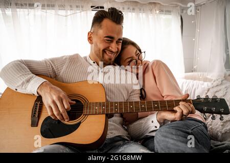 gai homme jouant de la guitare acoustique près de rire femme dans la bande-annonce Banque D'Images