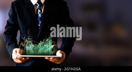 Homme d'affaires tenant un appareil intelligent avec hologramme de la bourse et graphique de forex avec analyse du marché boursier, business et le concept de marché de négociation. Banque D'Images