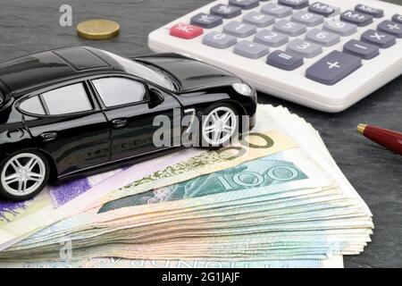 Une voiture de luxe se trouve sur une pile de notes de kroner suédois avec une calculatrice en arrière-plan. Une métaphore sur le financement automobile. Banque D'Images