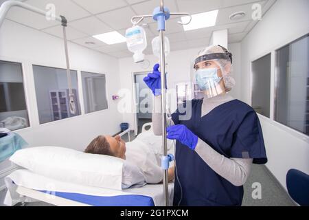 Patient adulte allongé sur le lit lors d'une injection intraveineuse en déposant une bouteille dans la clinique de l'hôpital Banque D'Images