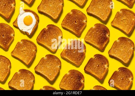 Pain frit jusqu'au brun doré, œufs brouillés pour le petit déjeuner. Des glucides croquants sur fond jaune vif. Vue de dessus. Banque D'Images