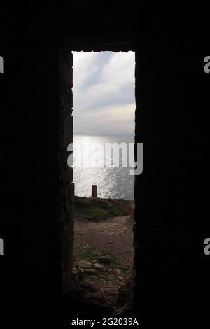 Towanroath Pumping Engine House Chimney et vue sur la mer encadrée par la mine de Coates de wheal Winding House entrée. St Agnes, North Cornwall, Royaume-Uni. Banque D'Images