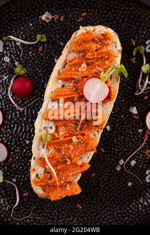 Baguette de grain entier saine avec tartiner au poivre. Ajvar - délicieux plat de poivrons rouges, oignons et ail. Banque D'Images