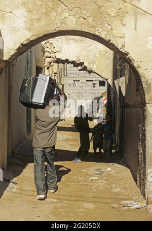 Homme portant un téléviseur sur son épaule dans la vieille médina de Tripoli, en Libye Banque D'Images