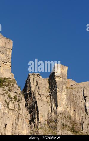 Preikestolen (rocher de Pulpit). 604 mètres / 1982 pieds au-dessus de Lysefjord. Les gens peuvent être vus assis sur le bord du toit plat de 25m x 25m. Banque D'Images