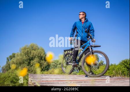 Un jeune cycliste se promette sur le pont de l'autre côté de la rivière Banque D'Images