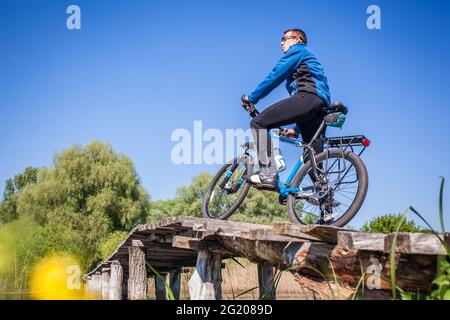 Un jeune cycliste se promette sur le pont de l'autre côté de la rivière Banque D'Images