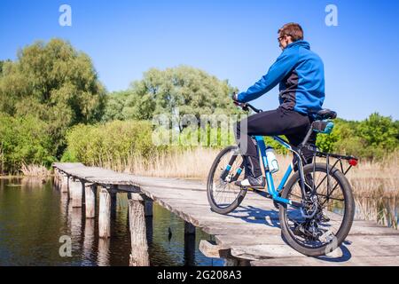 Un jeune cycliste se promette sur le pont de l'autre côté de la rivière Banque D'Images