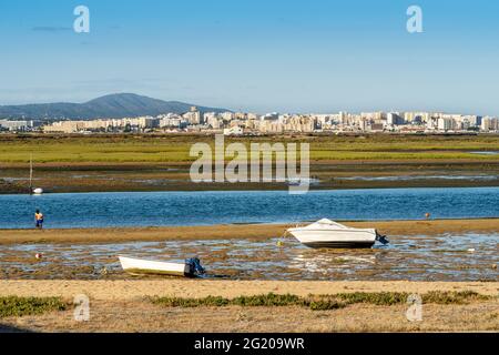 Ria Formosa à marée basse avec des bateaux et des gens qui rassemblent les fruits de mer, Faro, Algarve, Portugal Banque D'Images