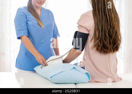 Jeune femme qui a vérifié sa tension artérielle par une infirmière, un médecin ou un visiteur de santé. Santé cardiaque. Moniteur de la jauge numérique de la pression artérielle. Banque D'Images