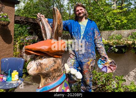 L'artiste Chris Rutterford peint une sculpture humoristique de lièvre en fibre de verre géant dans son studio de plein air pour un parcours artistique caritatif, en Écosse, au Royaume-Uni Banque D'Images