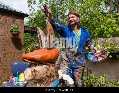 L'artiste Chris Rutterford peint une sculpture humoristique de lièvre en fibre de verre géant dans son studio de plein air pour un parcours artistique caritatif, en Écosse, au Royaume-Uni Banque D'Images