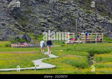 Touristes se baignant dans la source chaude à la vallée de Landmannalaugar, Réserve naturelle de Fjallabak, parc naturel près de Hekla / Hecla en été, Sudurland, Islande Banque D'Images