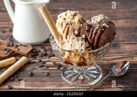 Glace Roma au chocolat, à la crème et au caramel dans un bol en verre avec une sauce au chocolat et aux noisettes. Banque D'Images