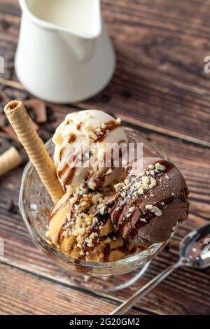 Glace Roma au chocolat, à la crème et au caramel dans un bol en verre avec une sauce au chocolat et aux noisettes. Banque D'Images