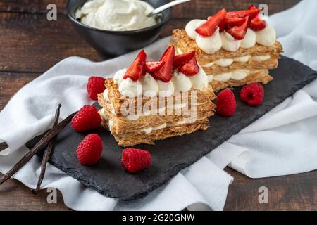 Fraises, framboises et crème mille feuille sur assiette en pierre noire Banque D'Images