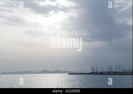 Magnifique paysage de la mer Égée à Athènes par temps nuageux. Silhouettes d'îles dans la brume. Voiles yachts près de la jetée. Banque D'Images