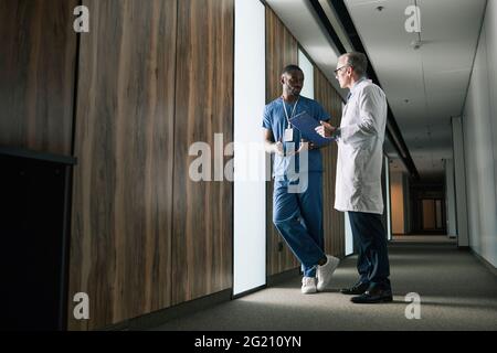 Portrait complet de deux médecins parlant en se tenant dans le hall de la clinique, espace de copie Banque D'Images
