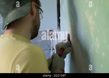 Homme caucasien enlevant la vieille peinture avec l'outil de racleur. Banque D'Images