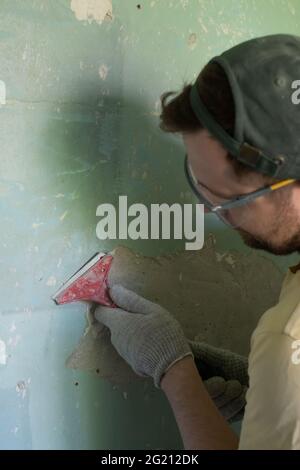 Homme caucasien enlevant la vieille peinture avec l'outil de racleur. Banque D'Images