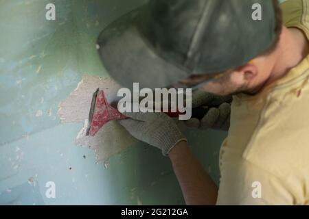 Homme caucasien enlevant la vieille peinture avec l'outil de racleur. Banque D'Images