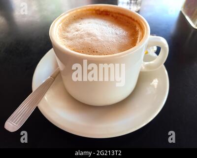 une tasse de lait mousseux et de café pour le petit déjeuner sur fond de table noire dans un café Banque D'Images