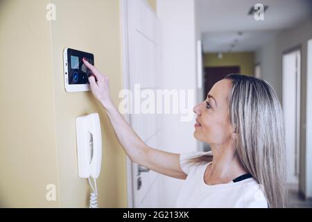 Une femme appuie sur les boutons du panneau de commande pour désarmer le système d'alarme antivol Banque D'Images