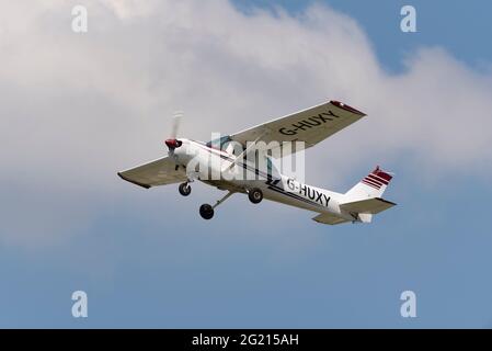 1979 Cessna 152 avion léger G-HUXY volant dans un ciel bleu clair au-dessus de l'aéroport Southend de Londres, Essex, Royaume-Uni. Grimpez dans une bonne visibilité avec le nuage léger Banque D'Images