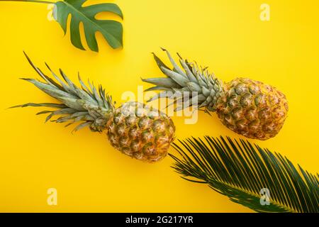 Ananas et feuilles de palmier sur fond jaune d'été. Fruits tropicaux d'été ananas plat composition de la couche. Banque D'Images