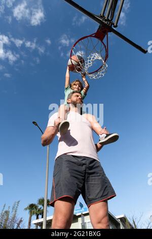 père et fils jouent au basket-ball en plein air. joyeux fête des pères. famille heureuse Banque D'Images