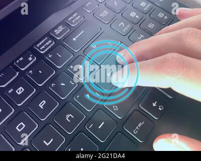 Gros plan d'une main en appuyant sur le bouton ENTER d'un clavier avec hud bleue en évidence Banque D'Images