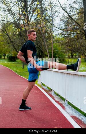 Coureur de sport noir s'étirant les jambes avant de faire l'entraînement matinal dans le parc public Banque D'Images