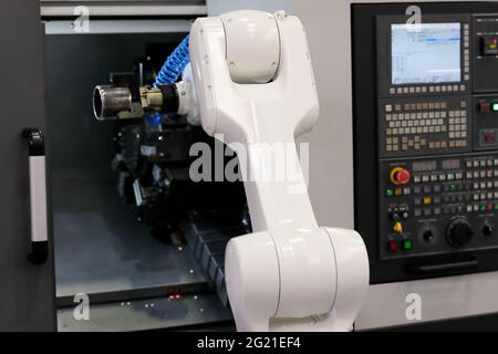 Chargement de la pièce par le robot dans la machine de tournage CNC. Mise au point sélective. Banque D'Images