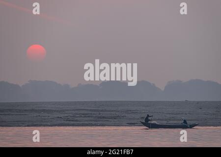 Pêcheurs en silhouette au lever du soleil sur la rivière Ganges à Varanasi, Uttar Pradesh, Inde Banque D'Images