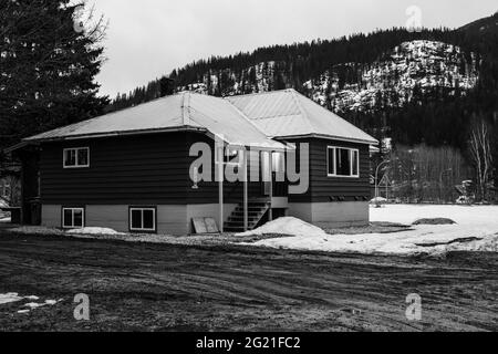 REVELSTOKE, CANADA - le 14 MARS 2021 : maison privée noire et blanche dans une petite ville heure du soir début du printemps avec de la neige Banque D'Images
