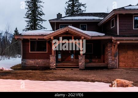 REVELSTOKE, CANADA - le 14 MARS 2021 : maison privée et vue sur la rue dans une petite ville en soirée, tôt le printemps avec de la neige Banque D'Images