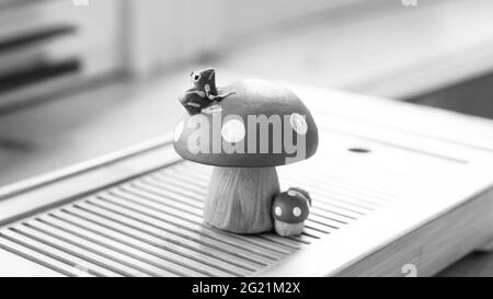 Une petite grenouille assise sur une mouche agaric. Figurine de thé en argile, théière. Photo en noir et blanc. Banque D'Images