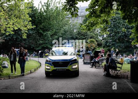 Un véhicule de police patrouille dans la rue en tant que gens, détendez-vous dans le parc vert de Stephen. Depuis avril 2021, Dublin a progressivement assoupli les restrictions, et avec les vacances en banque en baisse le lundi 7 juin, le réchauffement climatique et les toilettes publiques installées dans les rues, plusieurs personnes ont choisi de passer le week-end à socialiser à l'extérieur dans le centre-ville. La foule importante a provoqué des tensions telles que des bouteilles lancées contre la police, des personnes refusant de déménager lorsque la police les a demandées, et d'autres incidents qui ont entraîné 47 arrestations à ce jour. (Photo de Natalia Campos/SOPA Images/Sipa Banque D'Images