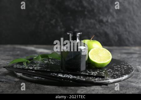 Diffuseur en roseau avec fruits sur fond sombre Banque D'Images